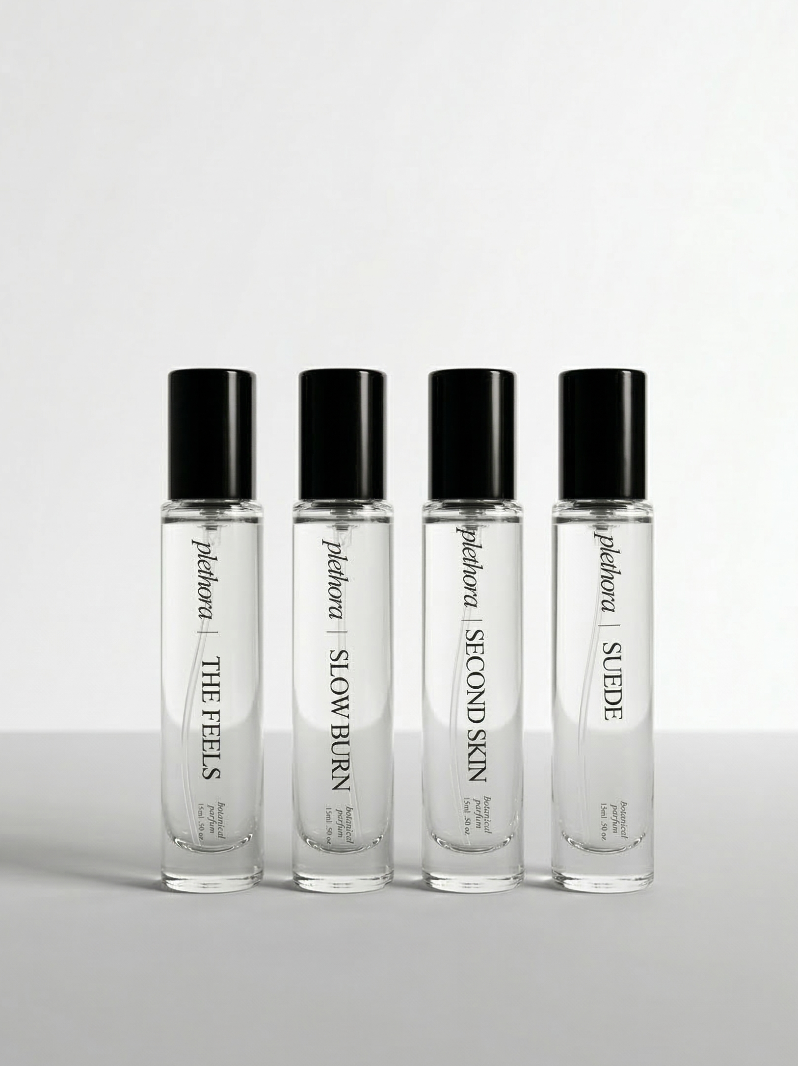 Four perfume bottles with black caps on a light gray background