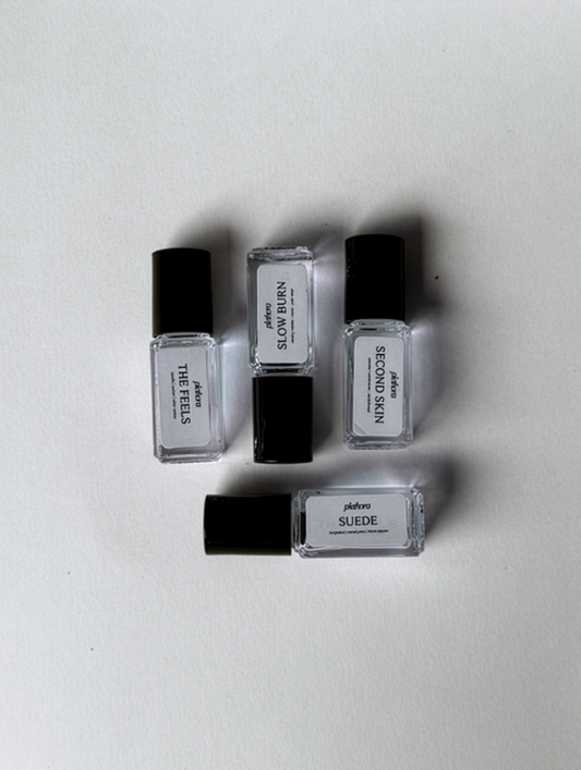 Four small bottles of perfume with black caps on a light gray background